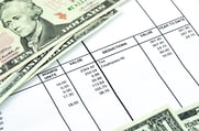 Some paper currency sits on top of a computer-generated pay stub. 