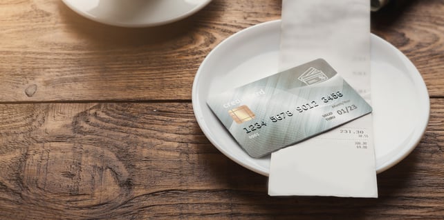 A dish holds a bill and a credit card on a restaurant table. 