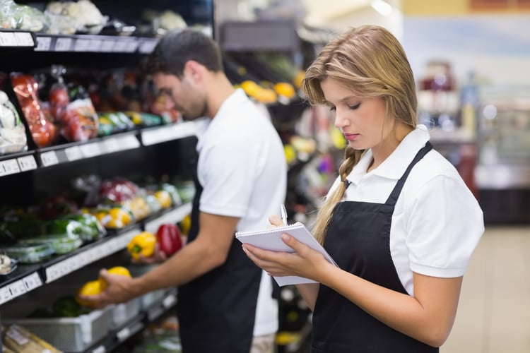 Serious staff woman wrting on notepad at supermarket-1