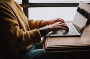 A woman is typing on a laptop.